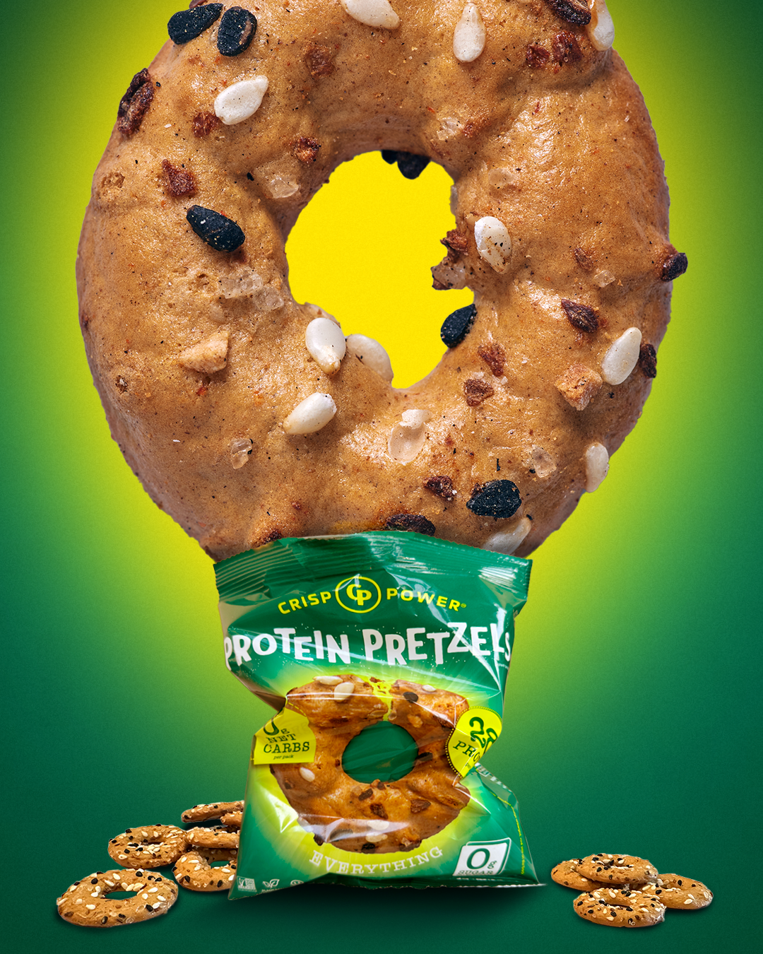 A large protein pretzel ring sits above a green bag of Crisp Power Protein Pretzels Everything, with a few loose pretzels scattered at the bottom, set against a green gradient background.